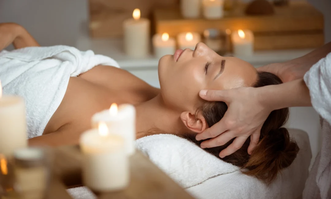 Young beautiful brunette girl having face massage relaxing in spa salon. Eyes closed. Copy space.